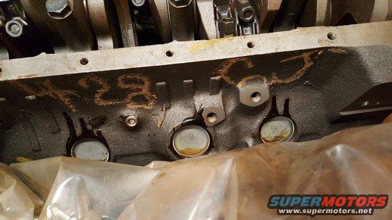 Close-up of an engine block with chalk markings that appear to say "X28"