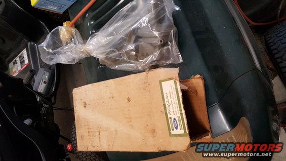 Ford part in cardboard box with plastic-wrapped component. Box has a Ford label