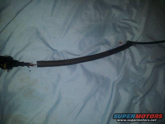Damaged black electrical wire with exposed copper strands