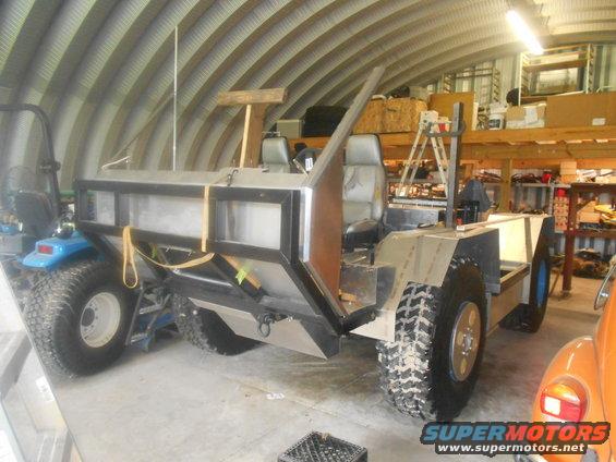 Custom off-road vehicle with large tires and metal bodywork, seen from a 3/4 front angle