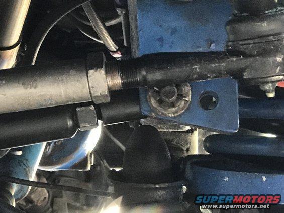 Close-up of vehicle steering linkage with blue painted bracket and silver tie rod