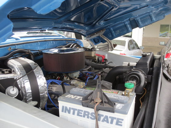 Engine bay showing air cleaner, Interstate battery, and radiator. Another vehicle is visible in the background