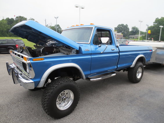 Blue Ford pickup truck with hood open, towing a trailer