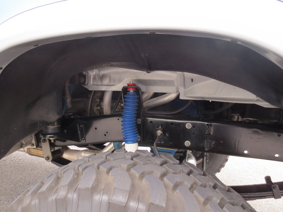 Close-up of a large truck tire and suspension components, including a blue shock absorber