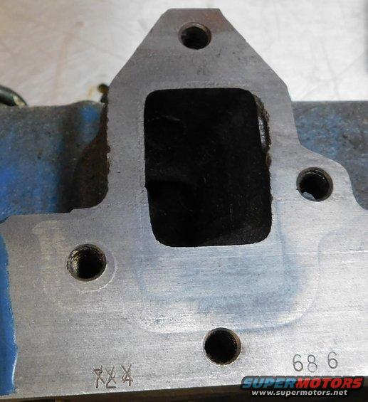 Close-up of an engine intake manifold part with stamped numbers '686' and 'XX4'