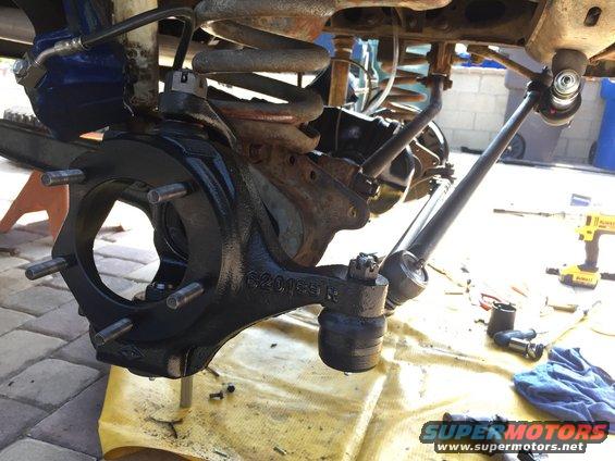 Black painted steering knuckle with wheel studs and ball joint, part number 62015R visible