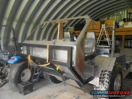 Custom off-road vehicle build in a garage, showing metal frame, seats, and tires