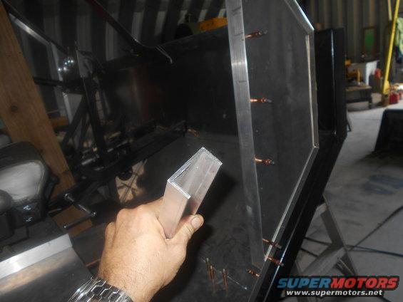 hand holding aluminum angle iron near metal panel with copper rivets