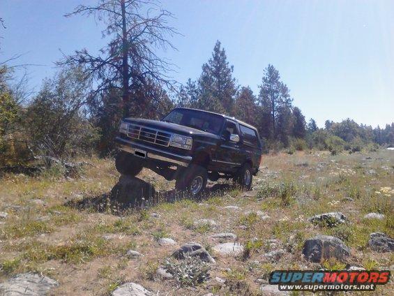 Black Ford Bronco driving over rocks on a dirt path