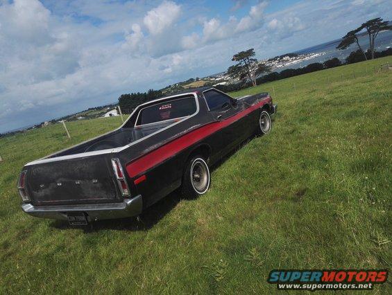 Black 1974 Ford Ranchero with red stripe, viewed from rear-left