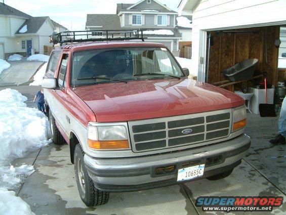 1996 Ford Bronco parked in driveway with snow piles and open garage