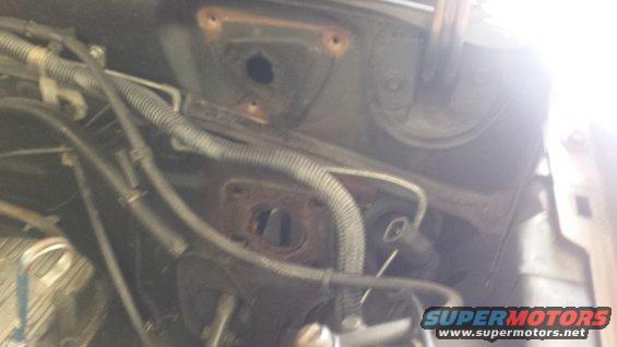 Engine bay with wiring and hoses, some rust visible