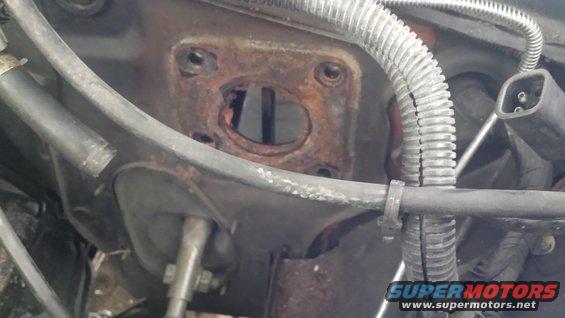 Rusted brake booster mounting plate with hoses and wiring