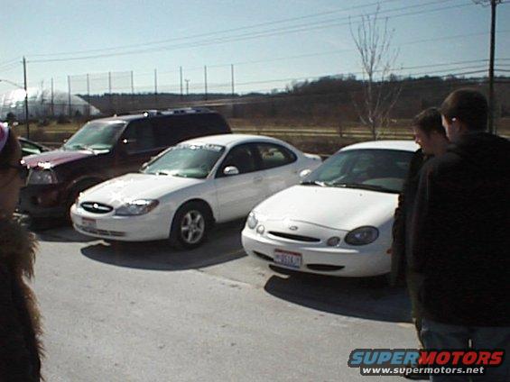 Two white Ford sedans and a dark SUV parked outside