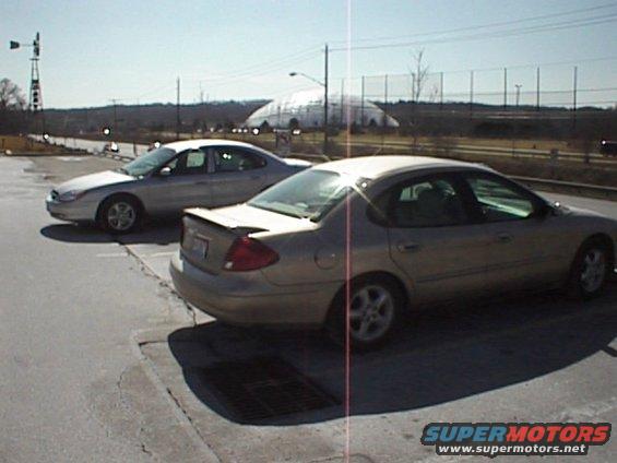 Gold 1999 Ford Taurus rear 3/4 view, parked next to a silver sedan