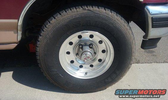 Close-up of a silver alloy wheel with a SALOM tire on a maroon vehicle
