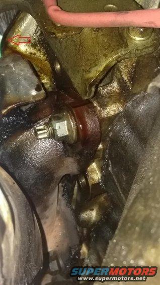 Engine part with a hex bolt, red fluid, and oil residue
