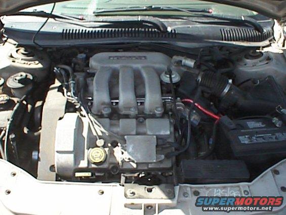 Engine bay of a 1999 Ford Taurus, showing the V6 engine, battery, and air intake system