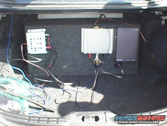Car trunk with a subwoofer box, amplifier, and wiring. A Sony amplifier is visible