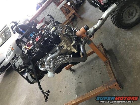 Engine on an orange engine stand with custom exhaust headers