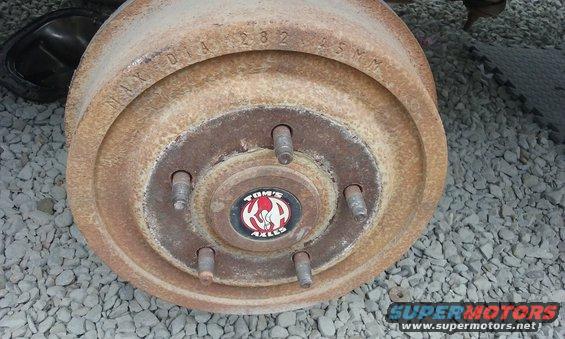Rusty brake drum with "Tom's Axles" logo and "MAY 01A 1282 45MM" stamped on it