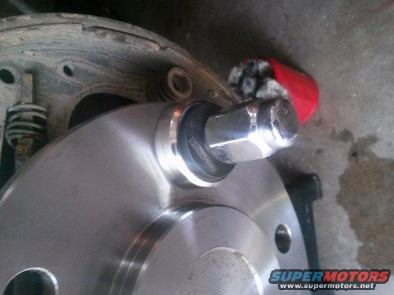 Wheel hub with lug nut and brake drum assembly. A red rag is visible in the background
