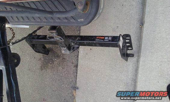 Trailer hitch receiver with CURT branding attached to a vehicle's rear bumper