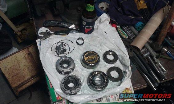 Transmission parts laid out on a table, including gears, bearings, and a "Warn" branded hub
