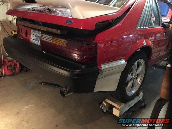 Rear bumper, taillights, and spoiler of a red car. License plate reads DEZMO