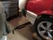 1983 Ford Mustang - The rear of a red car, likely a 1983 Ford Mustang, is shown in a garage with its bumper removed.