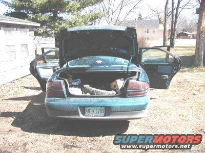 Green sedan's open trunk and rear doors reveal spare tire and interior. License plate reads 46 3789
