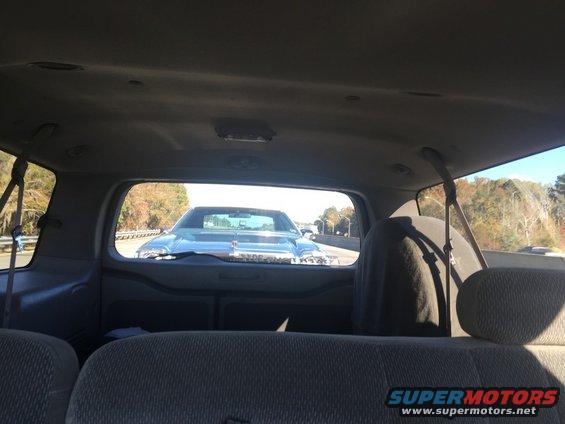 Light blue car's chrome grille and hood ornament seen from inside another vehicle