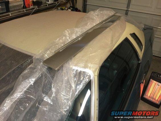Car roof covered in plastic with trim pieces on top. Heater in background