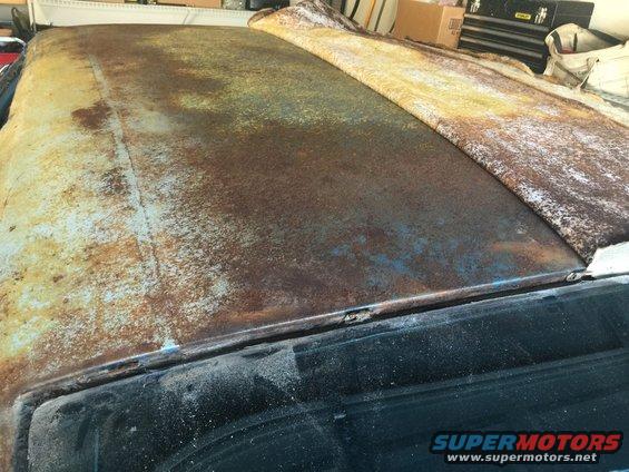 heavily rusted car roof with a tarp partially covering it