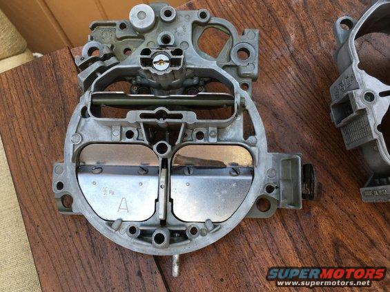 Close-up of a carburetor with two butterfly valves and visible part numbers