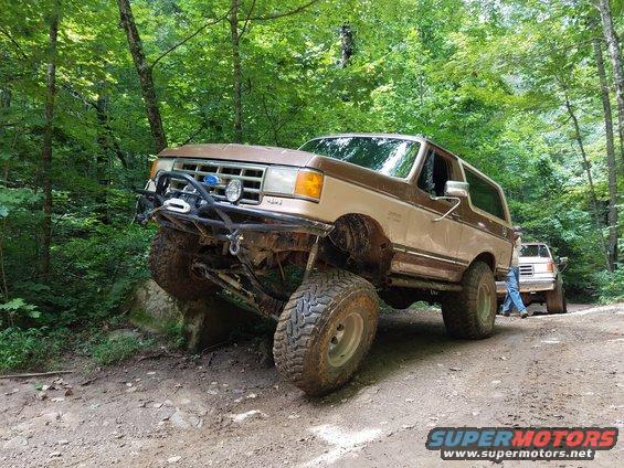 Brown SUV with large tires on a dirt road