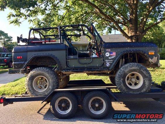 Side view of a lifted 1972 Ford Bronco with a roll cage, on a trailer