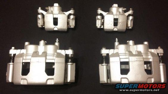 Four silver brake calipers laid out on a black surface. Text on one caliper reads '112'