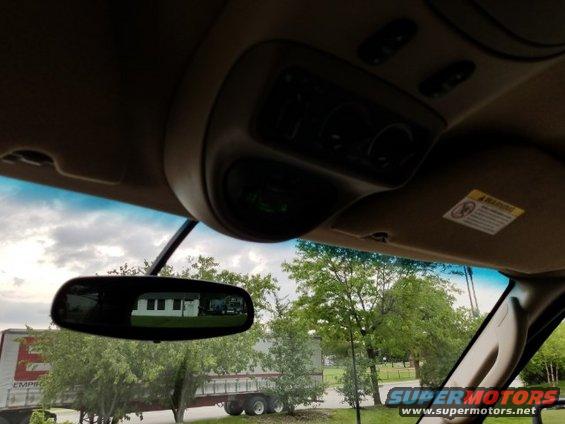 Interior overhead console and rearview mirror reflection showing a building and trees