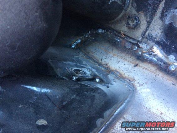 Welded metal frame with a threaded bolt hole. The metal shows signs of repair and modification