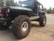 1995 Jeep YJ - Modified black Jeep Wrangler with prominent off-road tires and custom rocker panels is parked outdoors.