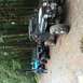 1995 Jeep YJ - A line of off-road vehicles are parked on a gravel path surrounded by dense trees.