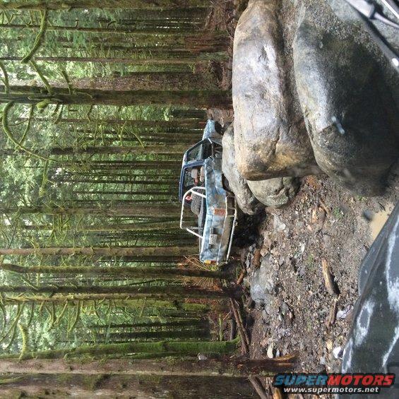 Blue Jeep Wrangler YJ with roll cage on rocky trail