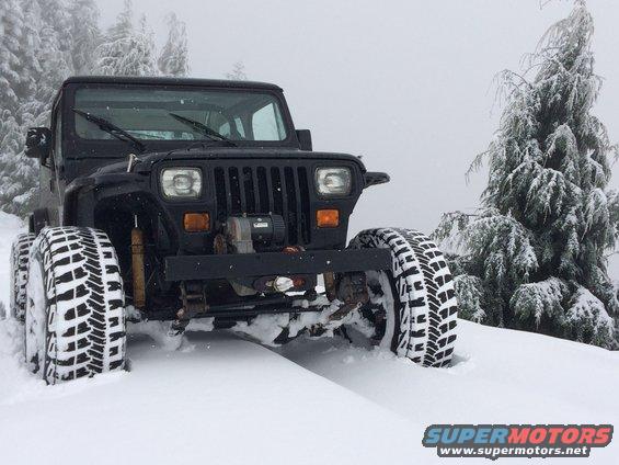 Black Jeep Wrangler in snow, front view, with winch and aggressive tires