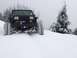 1995 Jeep YJ - A black 1995 Jeep YJ navigates a snowy mountain pass, its tires kicking up snow as it moves through the winter landscape.