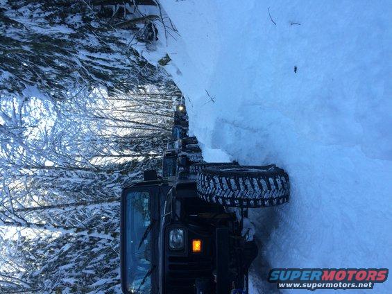 Several Jeeps driving on a snowy trail through trees