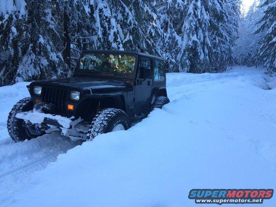 Black Jeep Wrangler stuck in deep snow, front view with winch