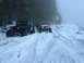 1995 Jeep YJ - Two Jeep Wranglers navigate a snow-covered mountain road, with the black YJ in the foreground and a white JK behind it.