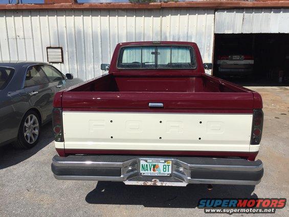Maroon and cream Ford F-150 pickup truck rear view, showing tailgate with 'FORD' lettering and a license plate