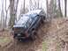 1978 Ford Bronco - A black SUV navigates a steep, wooded incline with its tires angled on the dirt.